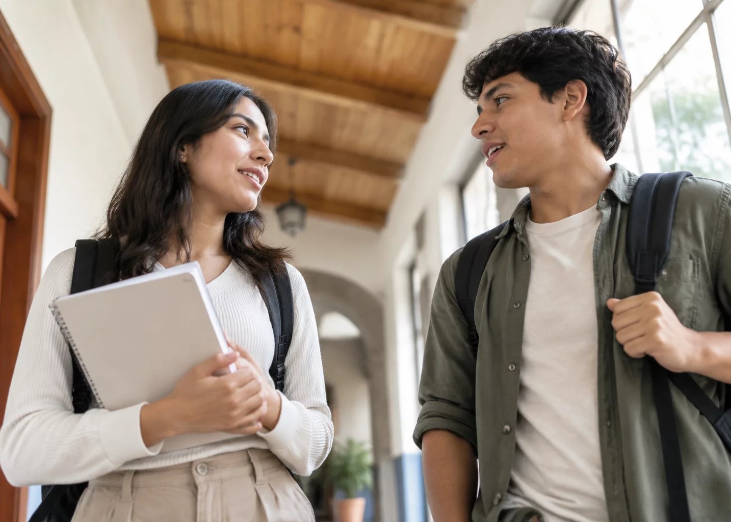 Dos jóvenes con mochila, charlando en un pasillo